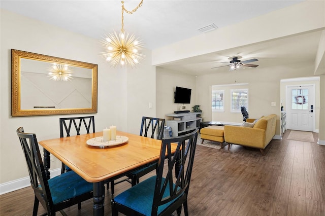 dining room featuring dark wood-style floors, ceiling fan with notable chandelier, visible vents, and baseboards