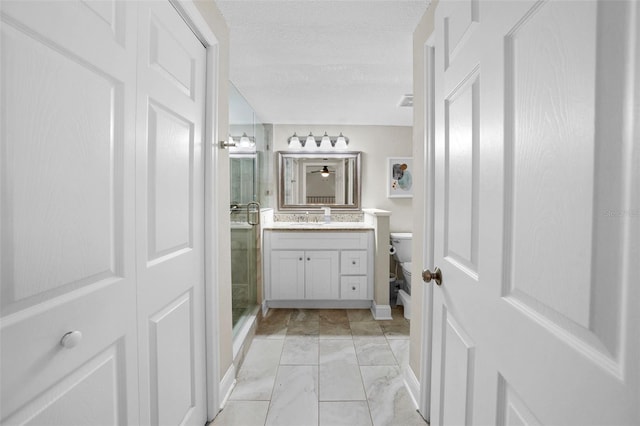 full bathroom with marble finish floor, toilet, a stall shower, vanity, and a textured ceiling