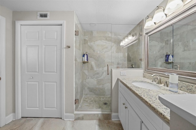 full bathroom with vanity, a shower stall, visible vents, and baseboards