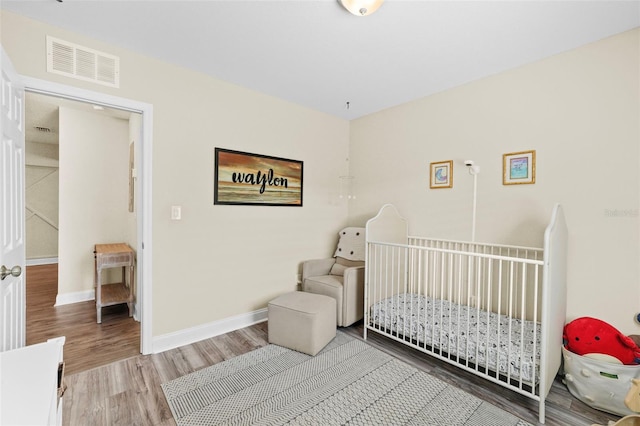 bedroom featuring light wood-type flooring, visible vents, and baseboards