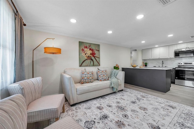 living room with sink and light hardwood / wood-style flooring