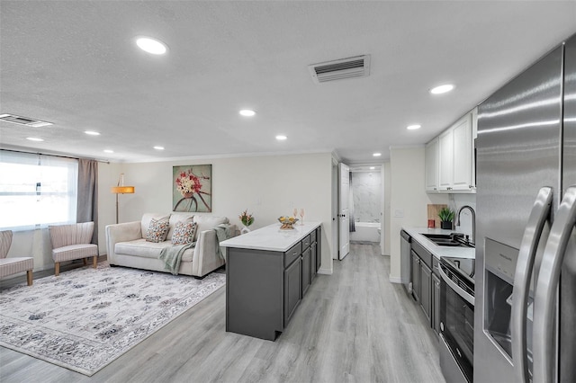 kitchen featuring sink, appliances with stainless steel finishes, white cabinetry, gray cabinetry, and a center island