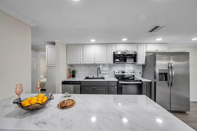 kitchen with light stone counters, stainless steel appliances, sink, and white cabinets