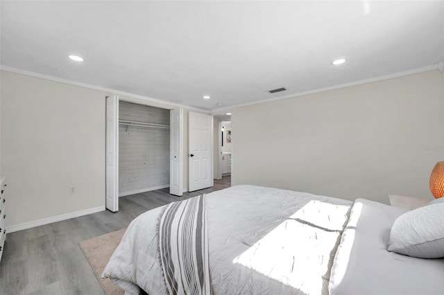 bedroom with crown molding, wood-type flooring, and a closet