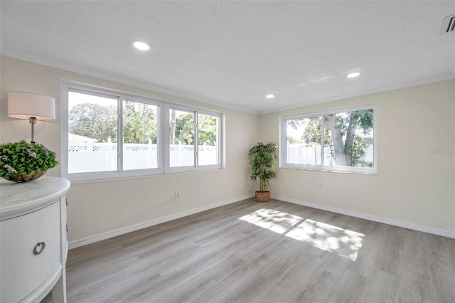 empty room with ornamental molding and light hardwood / wood-style flooring