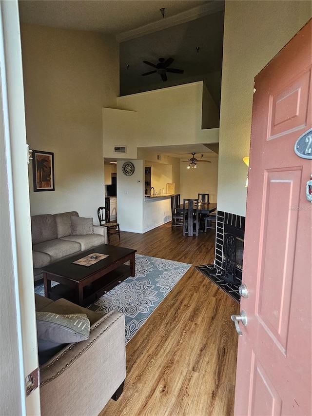 living room featuring wood-type flooring, a towering ceiling, sink, and ceiling fan