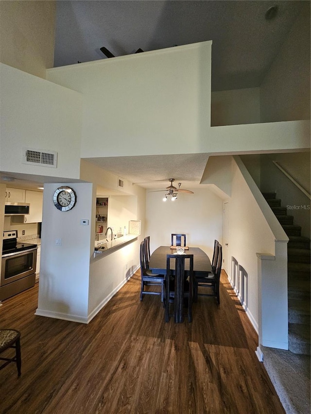 dining room with dark hardwood / wood-style flooring, sink, ceiling fan, and a high ceiling