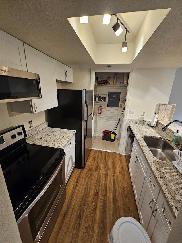 kitchen featuring sink, white cabinets, dark hardwood / wood-style flooring, a tray ceiling, and stainless steel appliances