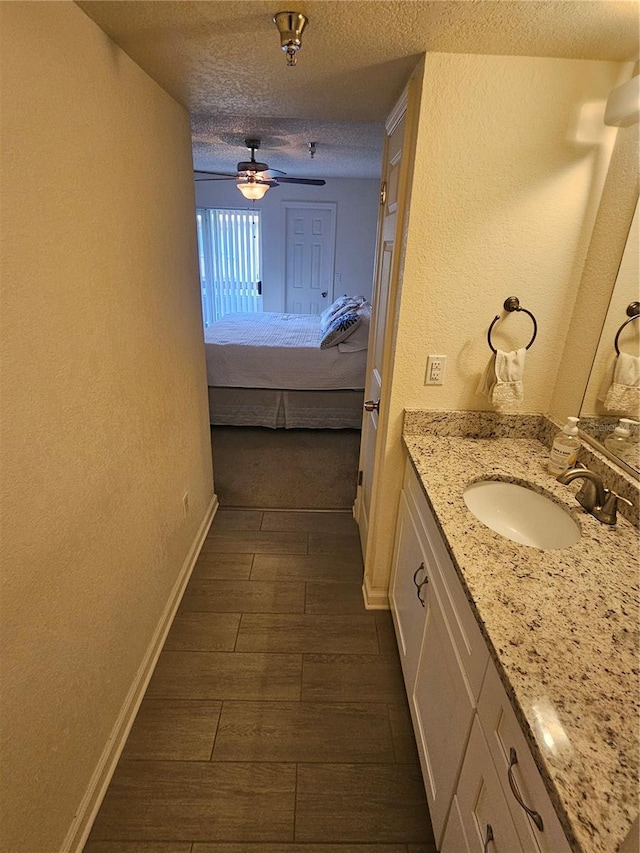 bathroom featuring vanity, ceiling fan, and a textured ceiling