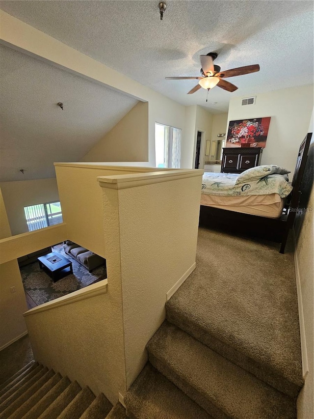 bedroom with ceiling fan, lofted ceiling, carpet flooring, and a textured ceiling