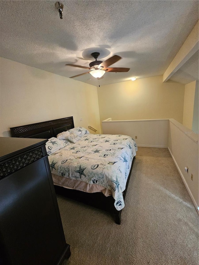 bedroom with beam ceiling, ceiling fan, carpet floors, and a textured ceiling