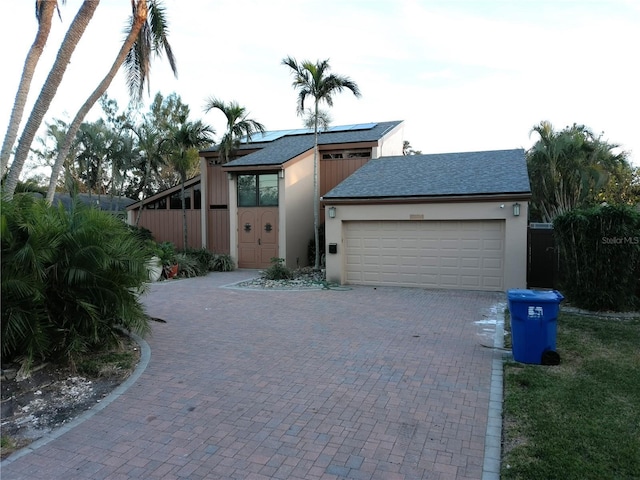 view of front of property featuring a garage and solar panels