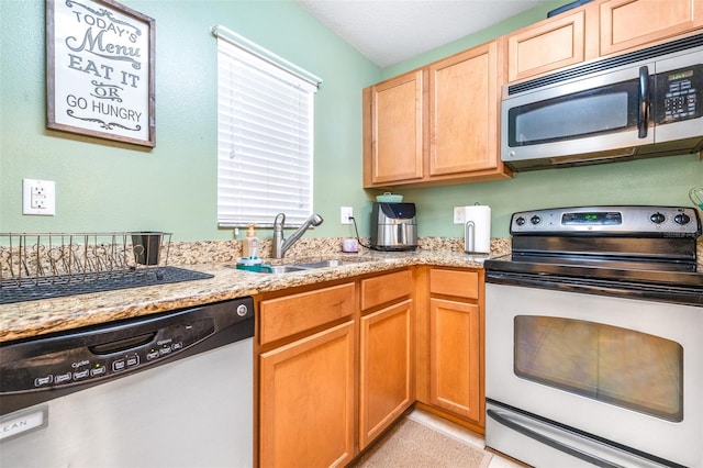 kitchen featuring stainless steel appliances, light stone countertops, and sink