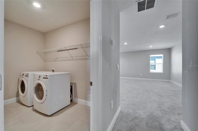 laundry area with light carpet, washer and dryer, and a textured ceiling