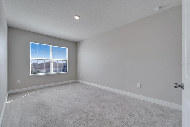 empty room with light carpet and a textured ceiling