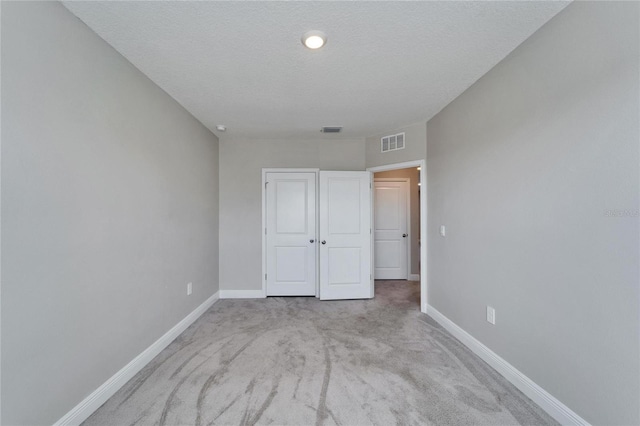 unfurnished bedroom with light carpet and a textured ceiling