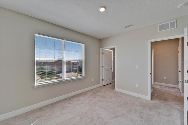 unfurnished bedroom featuring light colored carpet and a textured ceiling