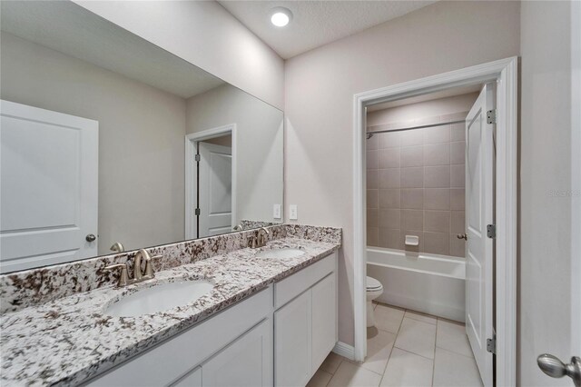 full bathroom featuring tile patterned floors, toilet, tiled shower / bath, a textured ceiling, and vanity