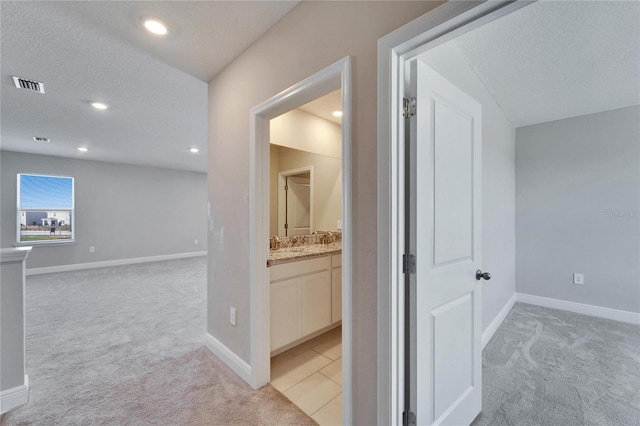 hall featuring light carpet and a textured ceiling