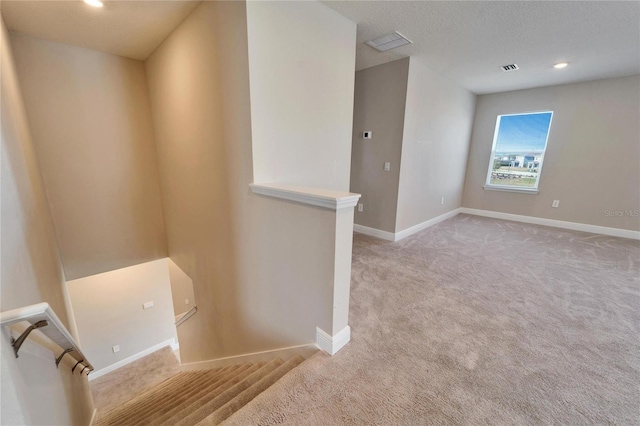 stairway with a textured ceiling and carpet flooring