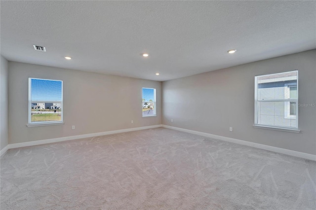 unfurnished room with light carpet and a textured ceiling