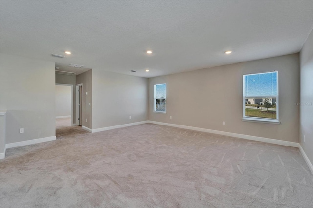 empty room featuring light colored carpet and a textured ceiling