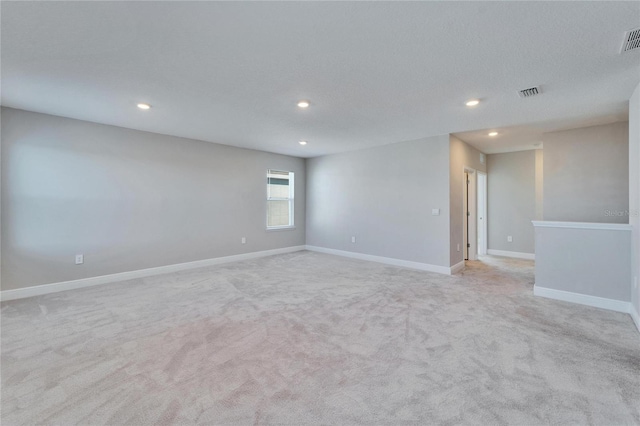 spare room with light carpet and a textured ceiling