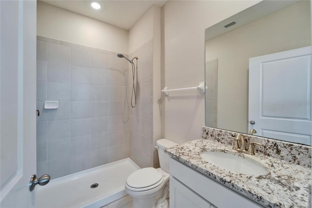 bathroom with vanity, toilet, and tiled shower