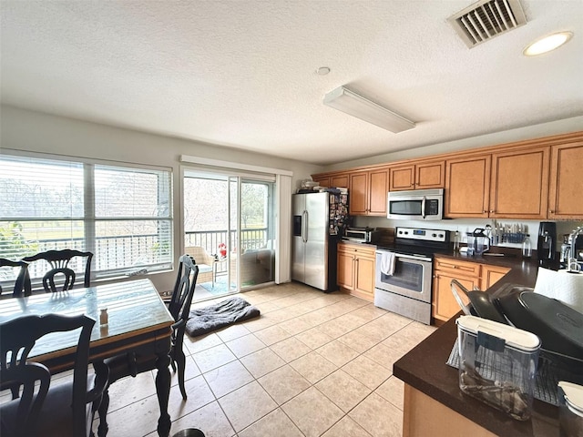 kitchen featuring appliances with stainless steel finishes, light tile patterned floors, and a textured ceiling