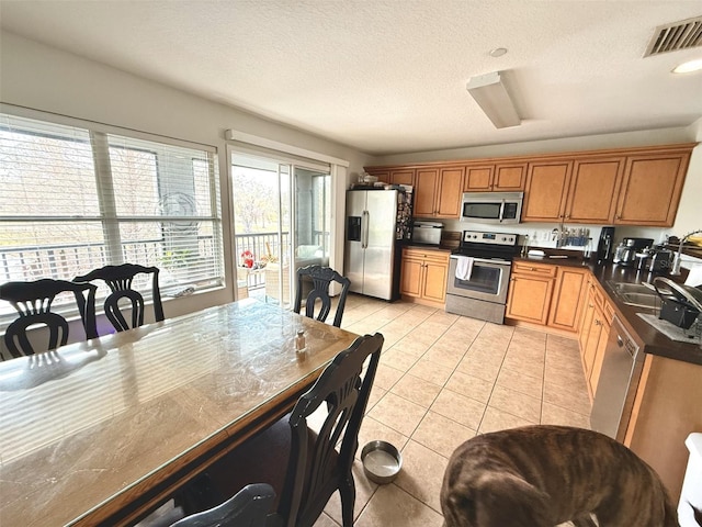 kitchen featuring stainless steel appliances, sink, a textured ceiling, and light tile patterned floors