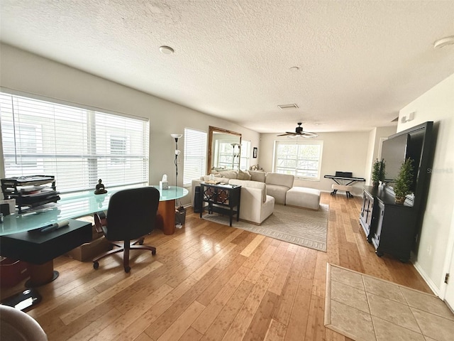 living room featuring ceiling fan, a textured ceiling, and light wood-type flooring