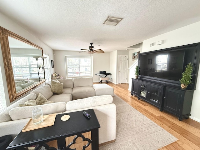 living room with ceiling fan, light hardwood / wood-style flooring, and a textured ceiling