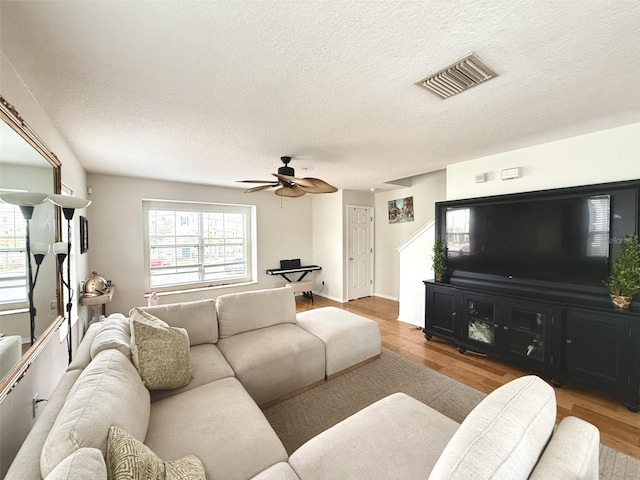 living room with ceiling fan, light hardwood / wood-style flooring, and a textured ceiling