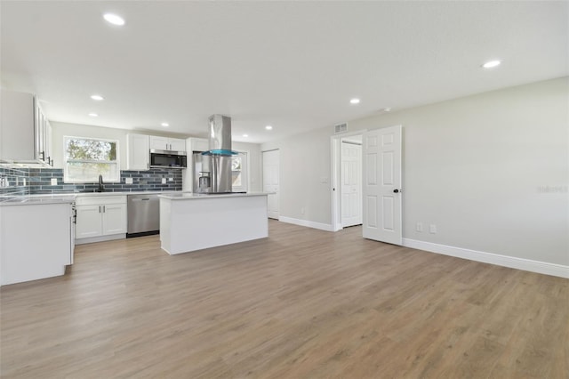 kitchen with a kitchen island, appliances with stainless steel finishes, white cabinetry, sink, and island exhaust hood