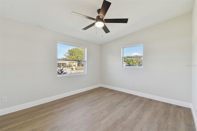 empty room with ceiling fan, vaulted ceiling, light hardwood / wood-style flooring, and a wealth of natural light