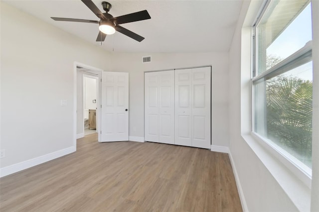 unfurnished bedroom with light hardwood / wood-style flooring, a closet, and ceiling fan