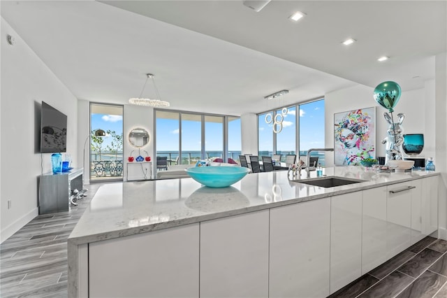 5120 Marina Way Unit 14002, Tampa, FL 33611 - kitchen with wood finish floors, a sink, white cabinets, expansive windows, and modern cabinets