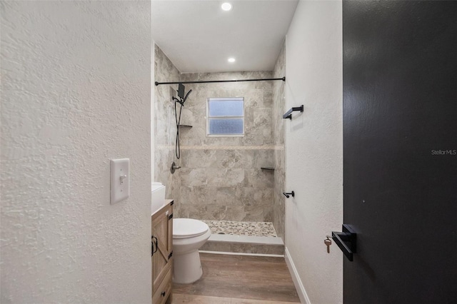 bathroom featuring toilet, wood finished floors, a stall shower, a textured wall, and vanity