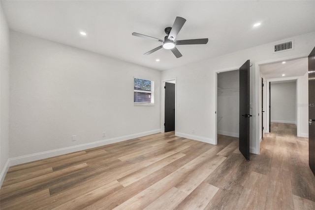 unfurnished bedroom with visible vents, a walk in closet, recessed lighting, light wood finished floors, and baseboards