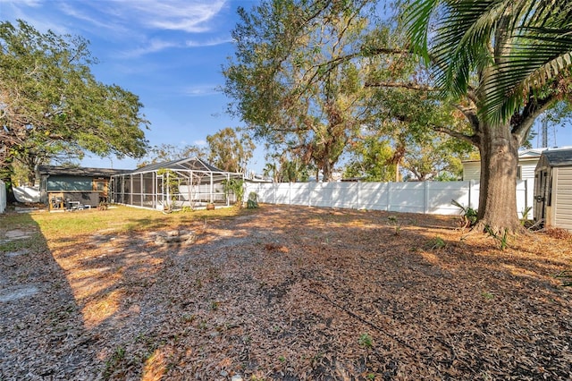 view of yard featuring glass enclosure, an outbuilding, a fenced backyard, and a shed