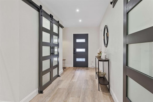 entrance foyer featuring light wood-type flooring, a barn door, baseboards, and recessed lighting