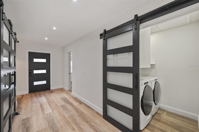 foyer featuring a barn door, baseboards, light wood-type flooring, and washer and clothes dryer