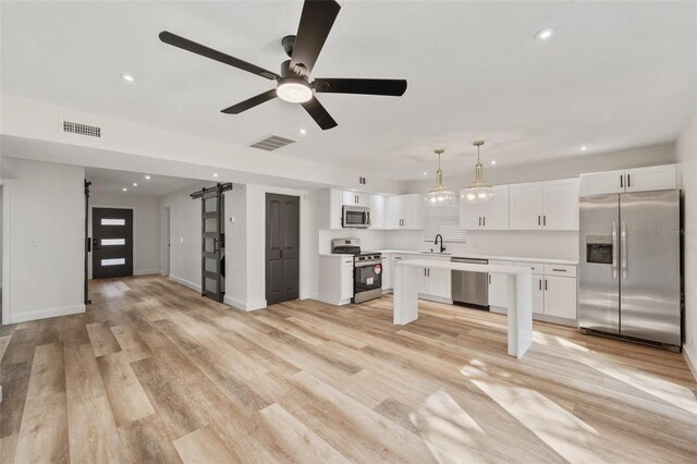 kitchen featuring stainless steel appliances, a barn door, visible vents, and light countertops