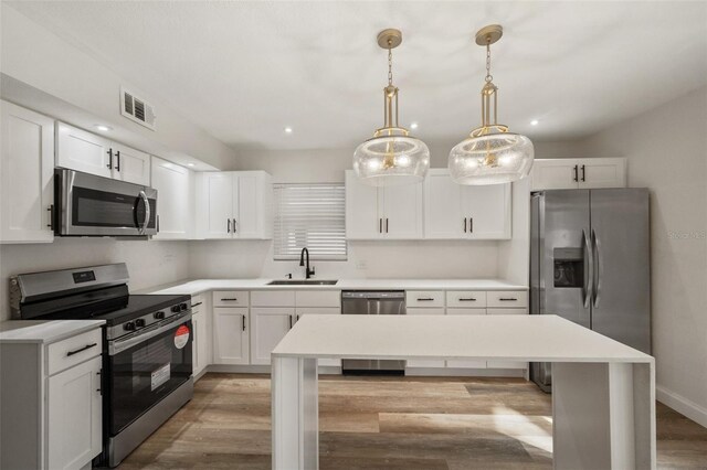 kitchen featuring visible vents, light countertops, light wood-style flooring, stainless steel appliances, and a sink