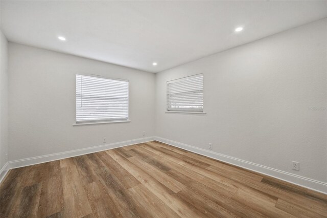 spare room featuring recessed lighting, baseboards, and wood finished floors