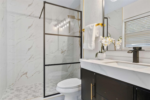 bathroom featuring a marble finish shower, toilet, and vanity