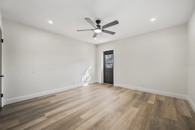 unfurnished room with a ceiling fan, wood finished floors, and baseboards