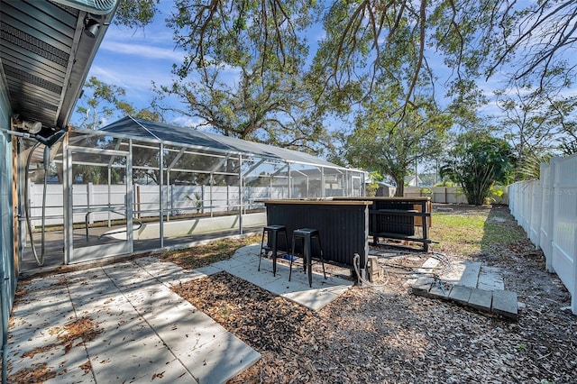 view of yard featuring a patio area, glass enclosure, outdoor dry bar, and a fenced backyard