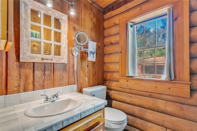 bathroom featuring vanity, log walls, and toilet