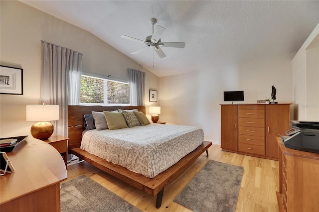 bedroom featuring lofted ceiling, a textured ceiling, ceiling fan, and light wood-type flooring